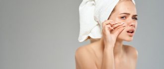 A girl with a towel on her head crushes a pimple on her neck